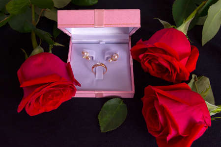 Red roses and pink gift box on dark background. Valentine's day, wedding or birthday concept