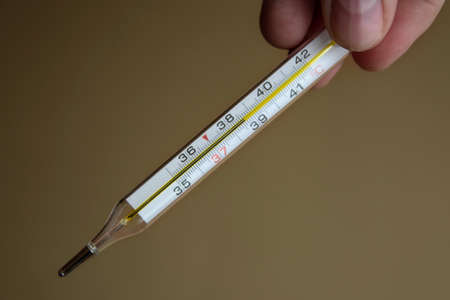 Medical thermometer for measuring body temperature in the hand in the foreground. High body...