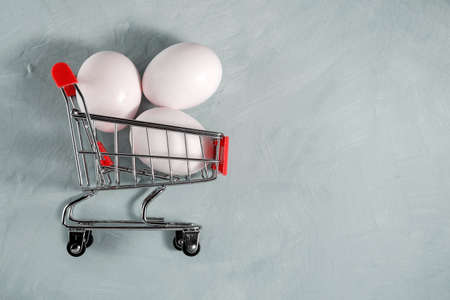 Basket with eggs on a gray background, sales concept, protein food, food product, diet dish, Easter, eggshell source of calcium, trolley full of productsの写真素材