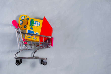A toy car and a house in a shopping cart. Side view. The concept of big purchases. Purchase on credit. Mortgage for buying real estate. Copy space.の写真素材