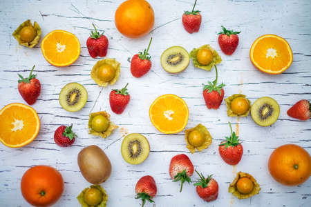 Fresh orange Kiwi and strawberries on the white wooden table, top viewの写真素材