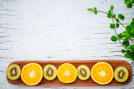 gold Kiwi and orange on wooden plateの写真素材