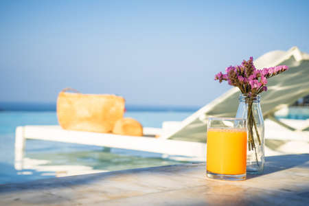 Bouquet of violet lilac in a vase ,orange juice sunglass and pool bedの写真素材