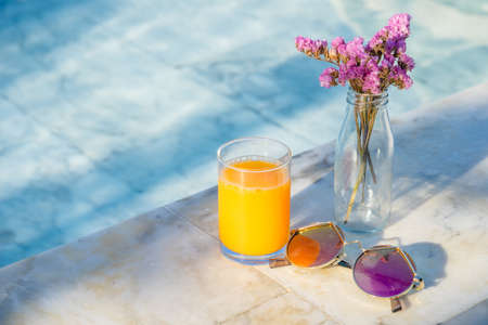 Bouquet of violet lilac in a vase ,orange juice sunglass and pool bedの写真素材