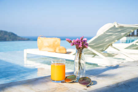 Bouquet of violet lilac in a vase ,orange juice sunglass and pool bedの写真素材