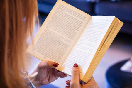 woman reading a book sitting on chair near the window