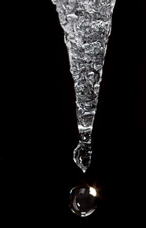 Thawing icicles dripping with white winter sky in backgroundの写真素材
