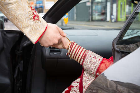 Groom assisting bride out of carの写真素材