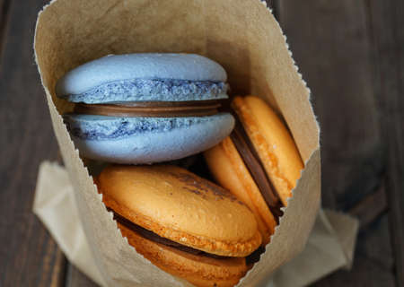 blue and orange macaroons in a backery paper bagの写真素材