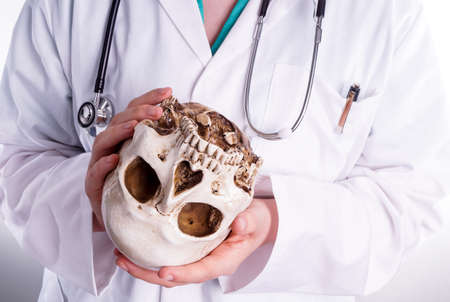 Doctor holding a skull in his hands. She shows the skull forward in a teaching situation or when she explains her patient what the patient study showedの写真素材