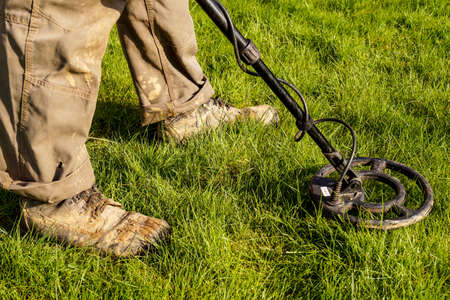 Metal Detector. Man with metal detector  he uses it to find archaeological treasures in the grass