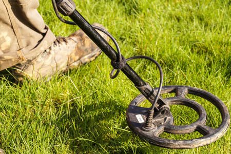 Metal Detector. Man with metal detector  he uses it to find archaeological treasures in the grass