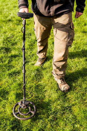 Metal Detector. Man with metal detector  he uses it to find archaeological treasures in the grass
