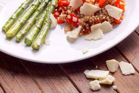 Vegetarian buckwheat risotto with red Bell peppers, served with grilled fresh green organic asparagus and garnished with fresh parmesan cheeseの写真素材