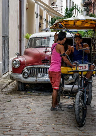 Havana, Cuba - January 5, 2016: Typical scene of one of streets in the center of La Havana - old cars and Rickshaw bicycle taxiのeditorial素材