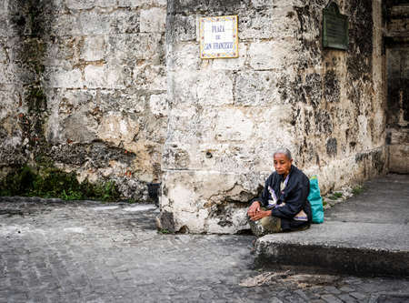 Havana, Cuba - January 8, 2016: Typical scene of one of streets in the center of La Havana - colonial architecture, and old woman sitting on the stairsのeditorial素材