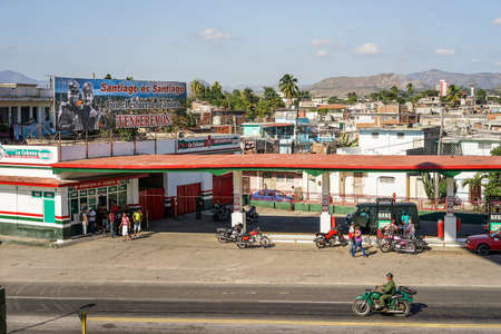Santiago de Cuba, Cuba - January 11, 2016: Typical scene of one of streets in the center of Santiago de cuba - Petrol stations where city residents can refuel their old American motorcycles and cars up. Over the tank is a poster with Raul Castro. Santiagoのeditorial素材