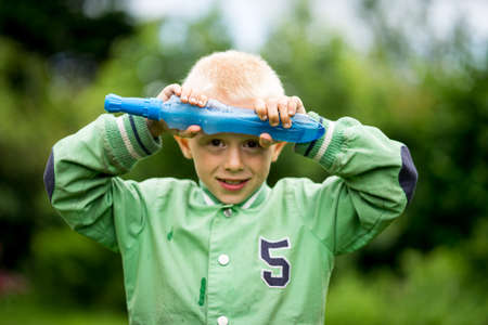 Little boy playing in the garden and have fun with blowing soap bubblesの写真素材