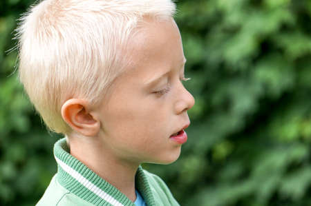Closeup portrait of a preschool boy with blurry gardenの写真素材