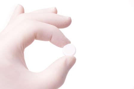 gloved hand holding small round pill. Hand and medicines are isolated on white backgroundの写真素材