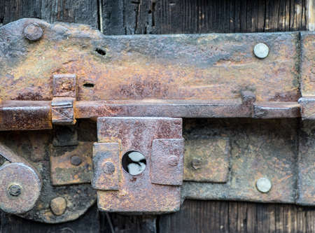 Detail of rusty iron door lock, rusty old latch lever lock, on a vintage wooden door