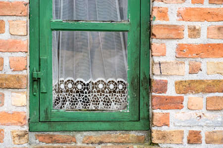 Green painted old cracked window with white lace curtains. Detail of vintage decorの写真素材