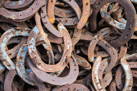 Heap of used and worn rusty Horseshoes outside blacksmith farriers shop or smithyの写真素材