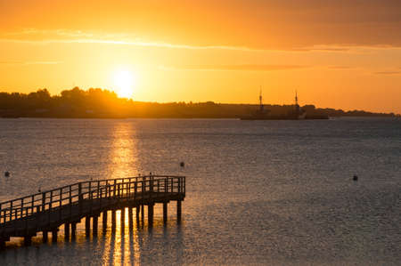 Beautiful sunrise in the summer over old wooden bridge and silent glossy sea. Sunrise over the sea. Pier on the foreground. Panoramaの写真素材