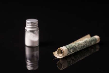 cocaine or other illegal drugs that are sniffed by means of a tube, isolated on black glossy backgroundの写真素材