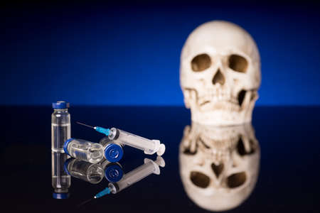 Skull, syringe and medical vials isolated on black blue background with glossy reflectionの写真素材