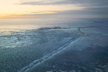 landscape of frozen lake with a large crack in the sunsetの写真素材