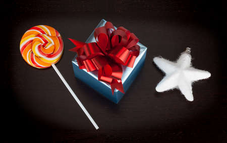 Blue gift box, candycane and white christmas star on black wooden 