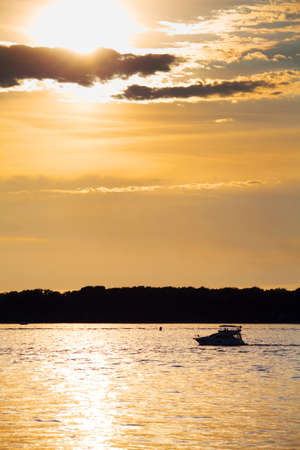 Cloudy sunset with silhouette of lonely boat の写真素材