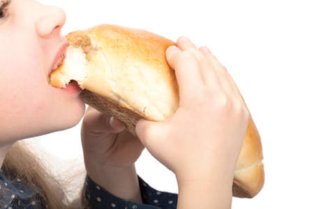 Little hungry girl biting a bun isolated on white background