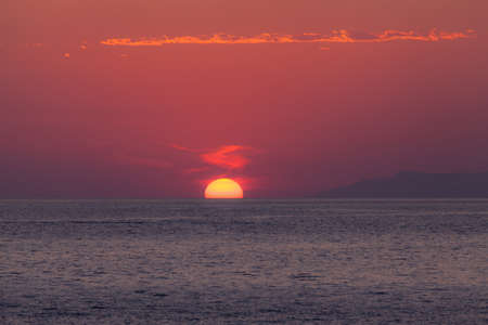 Amazing clowdy red dawn over seaの写真素材