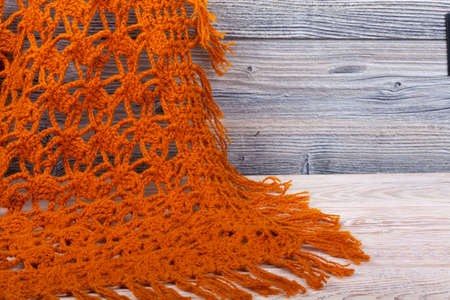 Traditional knitted woolen female shawl on wooden background