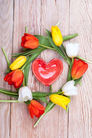 Heart shaped valentine gift with bunch of tulips on wooden backgroundの写真素材