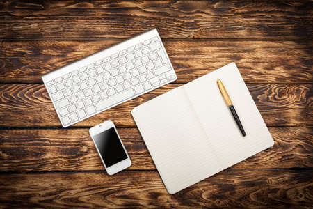 Working place view from above: keyboard, coffee, mobile phone on wooden backgroundの写真素材