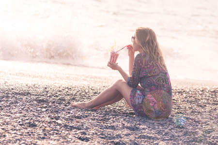 Beautiful woman on the beach with a glass of milk cocktailの写真素材