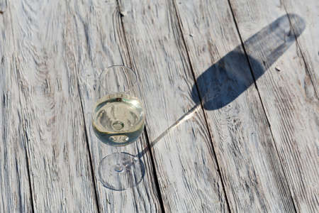 Glass of white wine on vintage wooden tableの写真素材