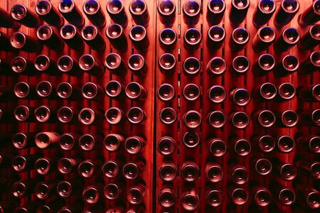 Bottle rack with wine bottles, image with a dominant red color but with a blue glow typical of this type of bottle, composition with a repeating pattern that reflects symmetryの写真素材