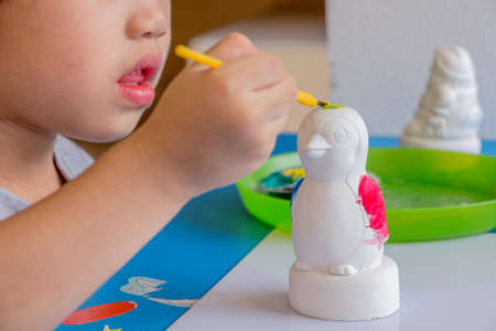 Little girl painting color on the plaster statueの写真素材