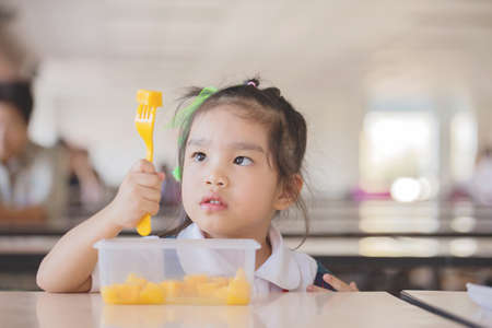 Healthy eating - child eating an  fruit, lots of fresh fruit on the table in front as after schoolの写真素材