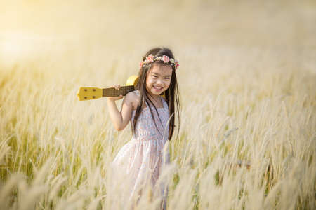 Little girl standing on meadow with sunsetの写真素材
