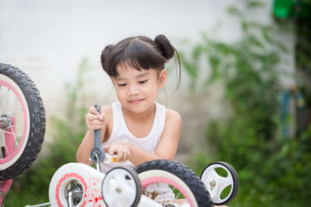 Little girl repairing a bicycleの写真素材