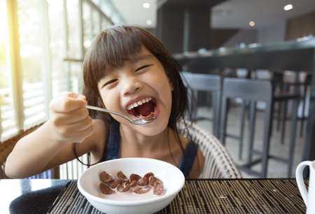 portrait of feeling happy  a young girl having breakfast on tableの写真素材