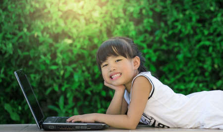 Happy little girl having fun play laptopの写真素材