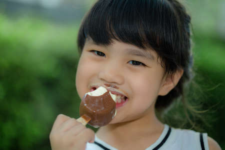 Pretty little girl eating an ice cream outdoorsの写真素材
