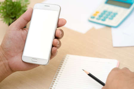 Businessman's hands holding and use mobile phone on on office table
