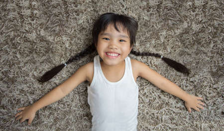 smiling cute little girl lying on the carpet